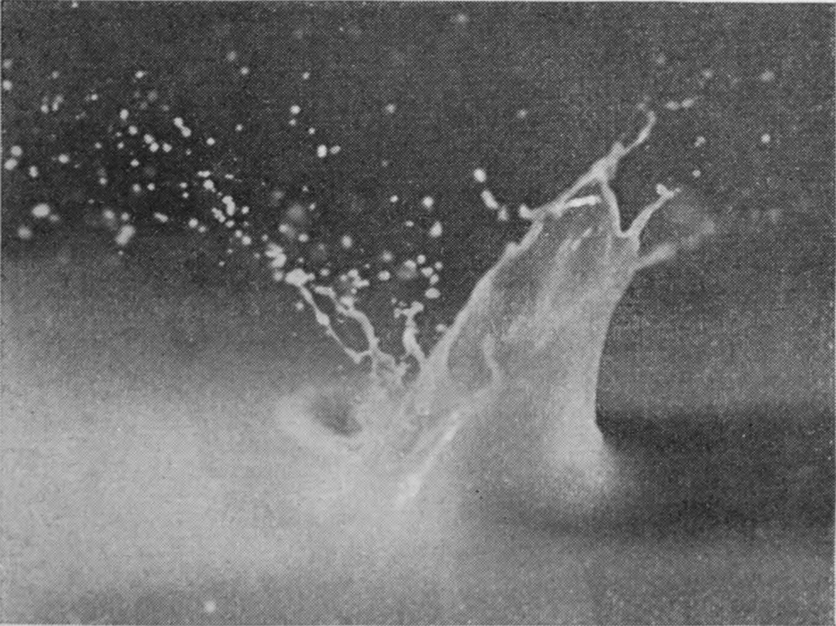 3 0·015 sec. — The sphere has vanished, leaving a tall one-sided crater wall whose top splits into jets and a spray of droplets.