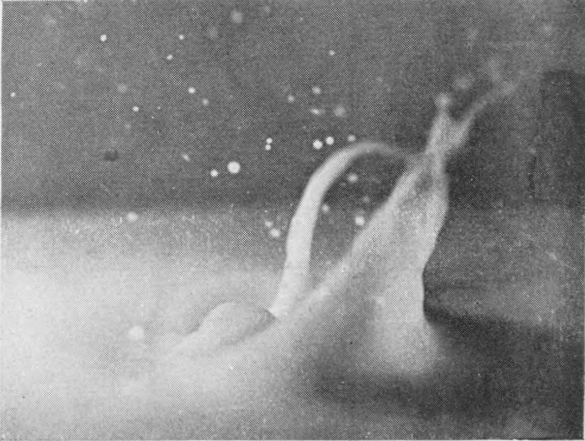 4 0·037 sec. — The crater falls back into a leaning column with an arching jet beside it, and droplets hang in the air above.