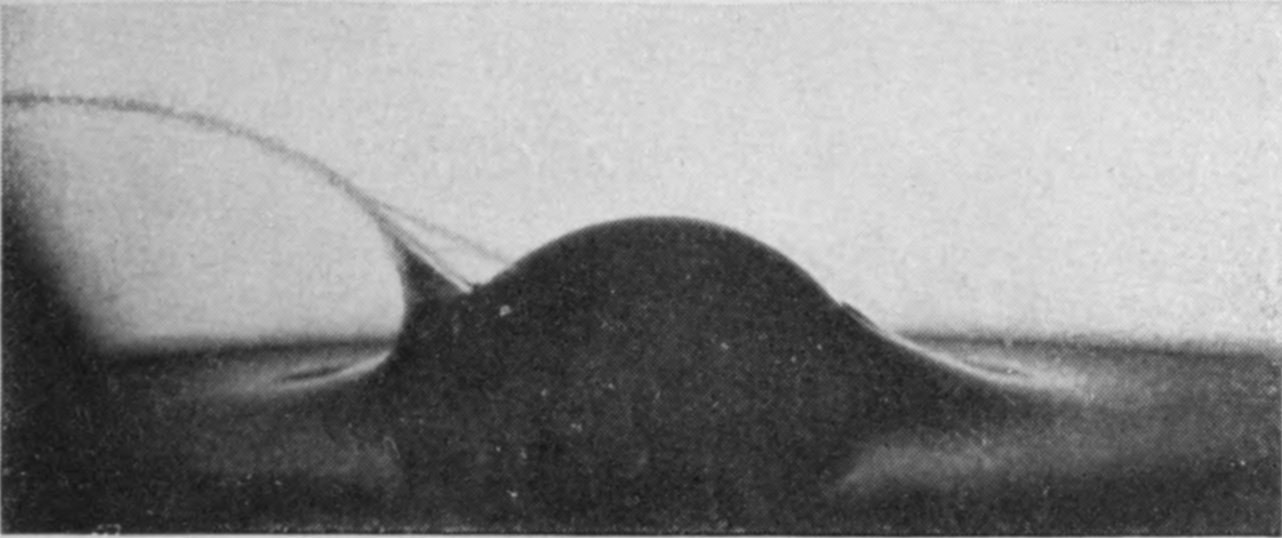 2 — The sphere sinks lower and a single long, isolated jet streams off to the left, stretched thin rather than breaking into droplets.