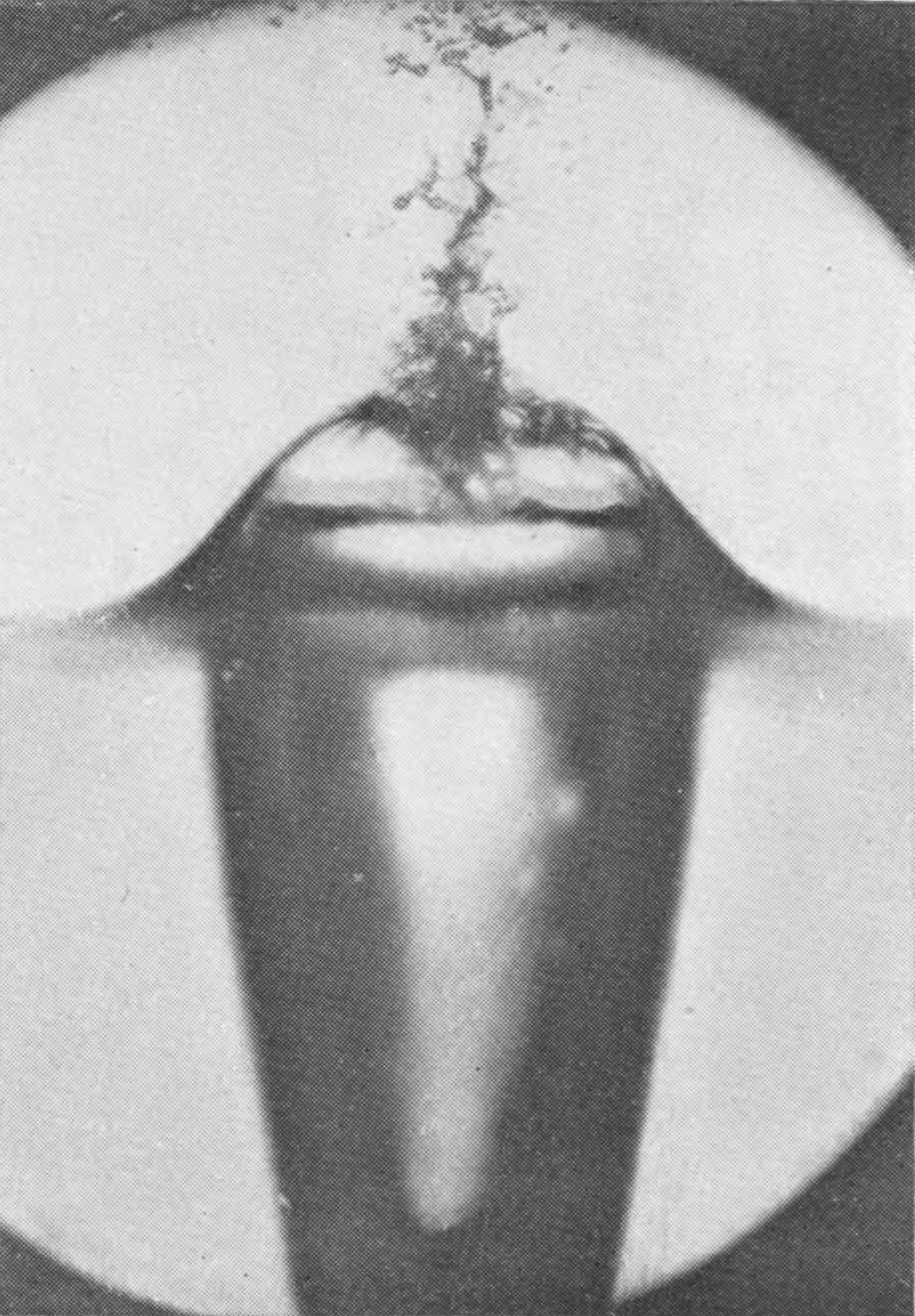 4 0·021 sec. — The closed bubble is lower and broader, with a ragged plume of spray rising from where the walls met; below the surface the air-tube widens as it descends.