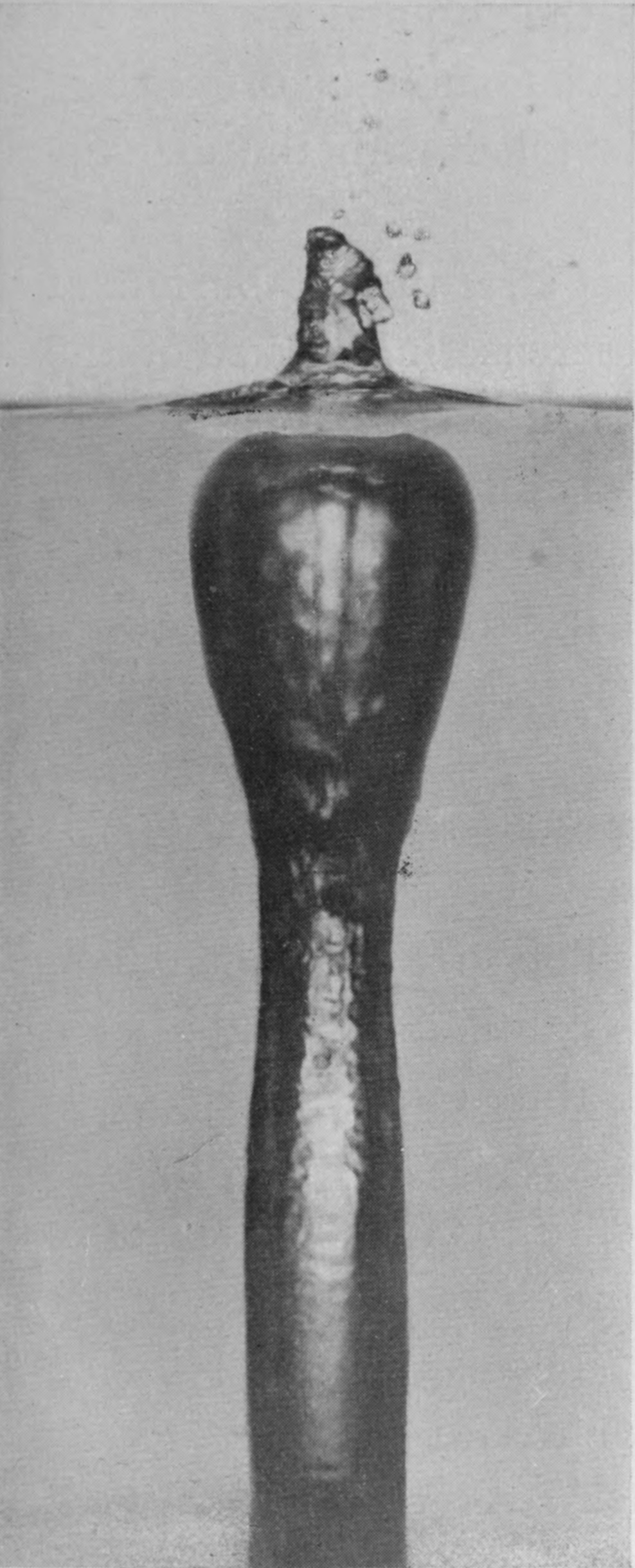 6 0·043 sec. — Upper and lower halves joined from two photographs. A small heap stands above the surface; below it a pear-shaped air-chamber narrows into the long air-tube, with the white jet shooting down its middle.