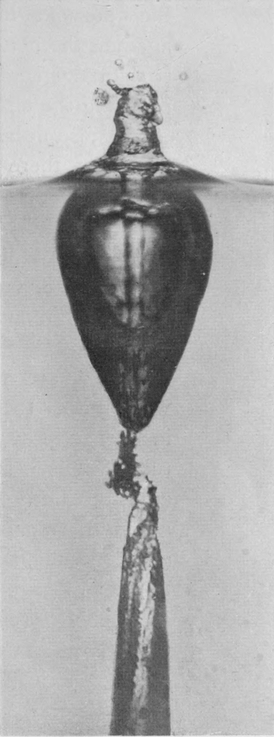 7 0·052 sec. — Made up from two photographs. The pear-shaped chamber tapers to a point, and below it the jet has struck the side and broken out in a ragged cloud of air-dust above the lower air-tube.