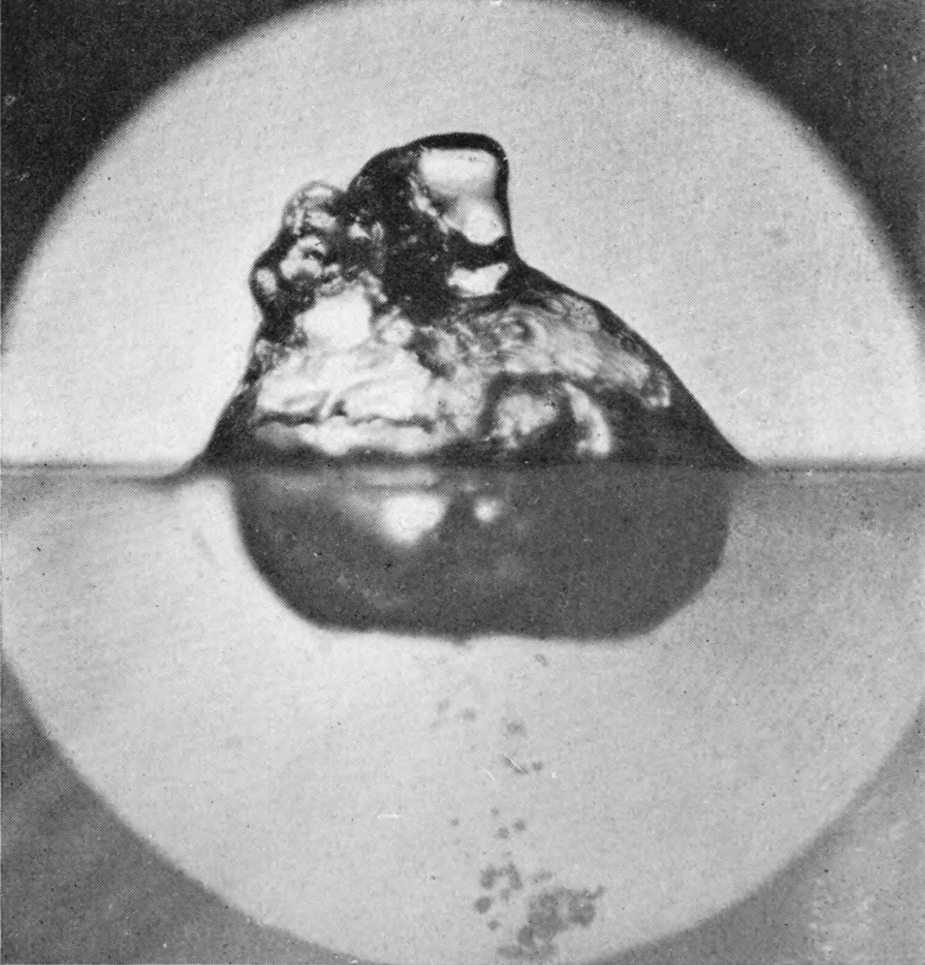 11 0·089 sec. — A large rough heap now stands above the surface, while the air-chamber below has flattened into a wide rounded pocket with scattered bubbles beneath.
